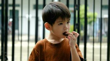 contento cara de asiático chico comiendo chocolate caramelo video
