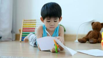 asiatico ragazzo utilizzando forbici per tagliare carta lungo Linee apprendimento al di fuori il aula video