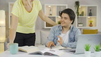 A mother who brings a drink to her son while he is studying gives him support and morale. video