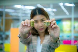 Young beautiful asian business woman held up a golden coin towards the camera. photo