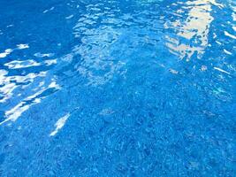 Surface of blue Swimming pool bottom caustics ripple and flow with waves background. Bright blue ripped water in swimming pool, Summer background. Texture of water surface. Top view. photo