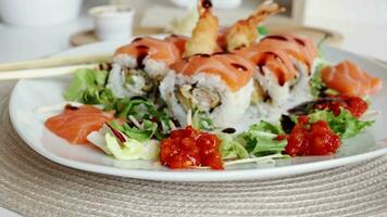 View of fusion salmon sushi rolls with sauce on white plate. Healthy and fusion japanese food style concept video