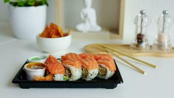 Sushi rouleau avec saumon, fumé anguille, avocat, crème fromage sur une noir assiette à maison. Sushi menu. livraison concept. Japonais aliments. video