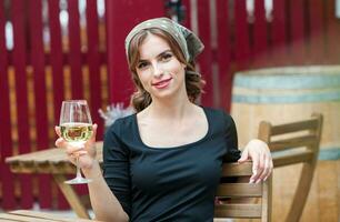 hermosa joven mujer Bebiendo blanco vino en el terraza de un restaurante. relajante después trabajo con un vaso de vino. soltero mujer teniendo divertida. foto