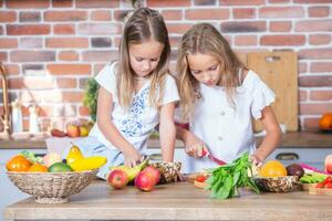 Two little girls in the kitchen with fresh vegetables. Healthy food concept.. Happy sisters photo