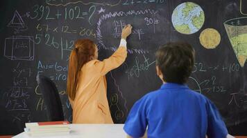 een leraar geeft les haar jongen leerling hoe naar Doen divisie. video