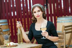 hermosa joven mujer Bebiendo blanco vino en el terraza de un restaurante. relajante después trabajo con un vaso de vino. soltero mujer teniendo divertida. foto