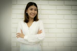 Portrait of a beautiful business woman in a close-up shot is standing with arms crossed and looking at the copy space with smile on her face. photo