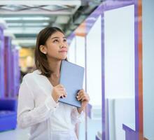 Pretty asian business woman stands sideways holding a tablet while smiling and looking directly at the copy space, Digital marketing. photo