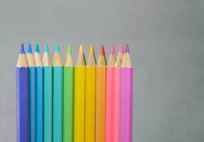 Color pancils with grey background, Group of colorful pencils laying in row striaght line made by pencil tips  close up, copy space, Pastel color,  Painting and Drawing concept. photo