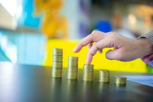 Business woman touching the third pile of coins from the right on black table, Finance and management concept, Concept of saving money for the future. photo