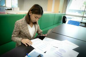 Beautiful asian businesswoman in close-up shot sitting and holding tablet with serious face in her office. photo