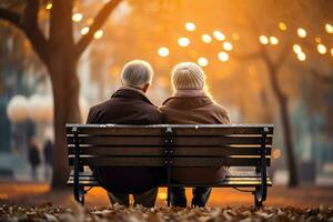 An elderly couple sitting on a park bench holding hands. Back view, soft bokeh background. AI Generated. photo