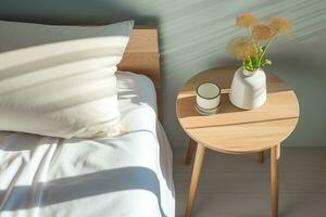 Wooden round table with a vase of dried flowers next to the white bed in the bedroom. The bright morning sun illuminates the interior, AI Generated. photo