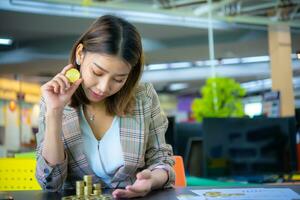 Young beautiful asian business woman holding a coin in one hand photo