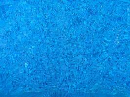 Surface of blue Swimming pool bottom caustics ripple and flow with waves background. Bright blue ripped water in swimming pool, Summer background. Texture of water surface. Top view. photo