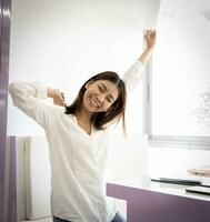 Vertical picture of beautiful asian business woman doing stretch oneself before starting work in her office. photo