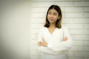 Portrait of a beautiful business woman is standing with arms crossed pretending to think in copy space with a doubtful expression. photo