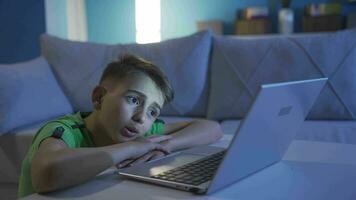 schattig weinig jongen op zoek Bij laptop met verbaasd uitdrukkingen. video