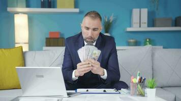 The businessman is calculating with the dollars in his hand at home. video