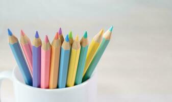 Color pencils in a white mug, Group of color pencils with white background, Copy space, Pastel color, Painting equipment, Drawing, Pastel colorful,  Education concept. photo