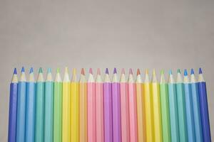 Group of color pencild laying in row striaght line made by pencil tips with grey background close up, Color pancils, copy space, Pastel color concept, Background concept, Education concept. photo