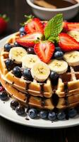 A plate of waffles with fresh fruit and chocolate chips photo