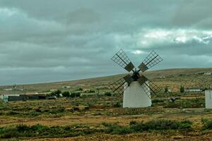 empty mysterious mountainous landscape from the center of the Canary Island Spanish Fuerteventura with a cloudy sky and original windmills photo