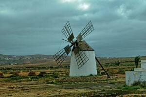 empty mysterious mountainous landscape from the center of the Canary Island Spanish Fuerteventura with a cloudy sky and original windmills photo