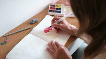 fermer de méconnaissable femme dessin avec aquarelle peindre, fabrication esquisser de une gâteau video