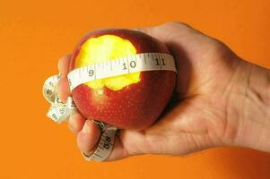 a person holding an apple with a measuring tape around it photo