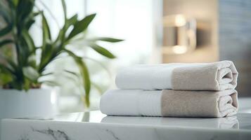 Towels on white marble desk in the foreground and blurred modern bathroom photo