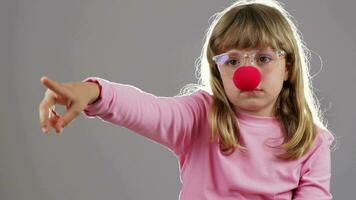 un pequeño niña con un rojo nariz señalando a alguna cosa video
