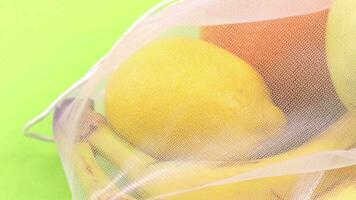 ein Gittergewebe Tasche gefüllt mit Obst auf ein Grün Hintergrund video