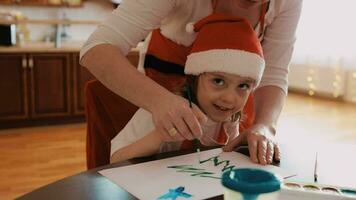 ein Frau und zwei Kinder im Santa Hüte beim ein Tabelle video