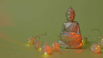 a buddha statue with a lit candle on a green background video