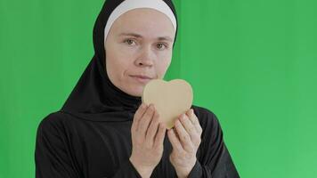 a woman in hijab holding a heart on a green screen video