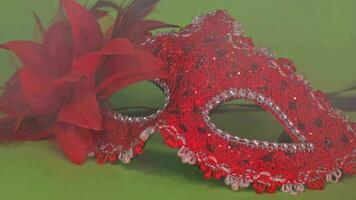 a red and black carnival mask with a red bow on the green background video