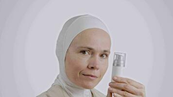 a woman in a hijab holding a bottle of cream video