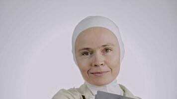a woman in a white headscarf holding books video