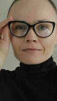 a woman wearing glasses and a black turtle neck video