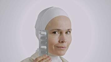 a woman in a white hijab holding a pill video