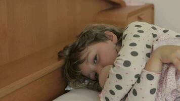 uma pequeno menina deitado dentro cama com dela cabeça em a travesseiro video