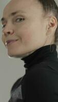 retrato de un contento mujer con un bollo peinado y un negro suéter tipo con cuello de tortuga video