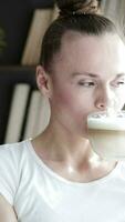 a woman is drinking from a cup of coffee while standing beside the window video