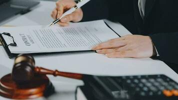 Business and lawyers discussing contract papers with brass scale on desk in office. Law, legal services, advice, justice and law concept picture with film grain effect video