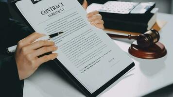 Business and lawyers discussing contract papers with brass scale on desk in office. Law, legal services, advice, justice and law concept picture with film grain effect video