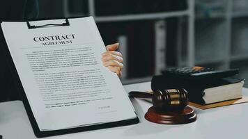 Business and lawyers discussing contract papers with brass scale on desk in office. Law, legal services, advice, justice and law concept picture with film grain effect video