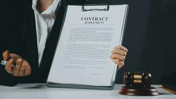 Business and lawyers discussing contract papers with brass scale on desk in office. Law, legal services, advice, justice and law concept picture with film grain effect video