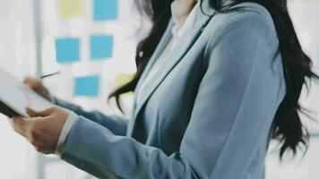 Young asian business woman working on project plan using sticky papers notes on glass wall, people meeting to share idea, Business design planning concepts. video